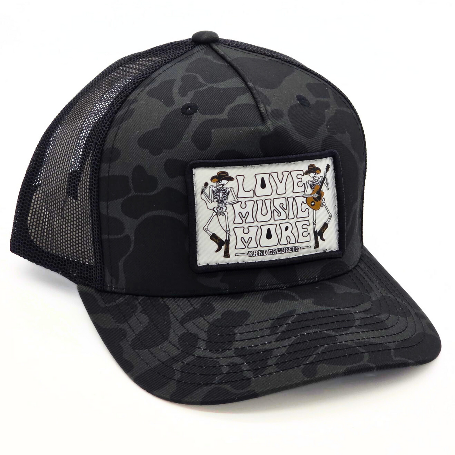 Black camouflage trucker hat with 'Live Music More' patch on a white background