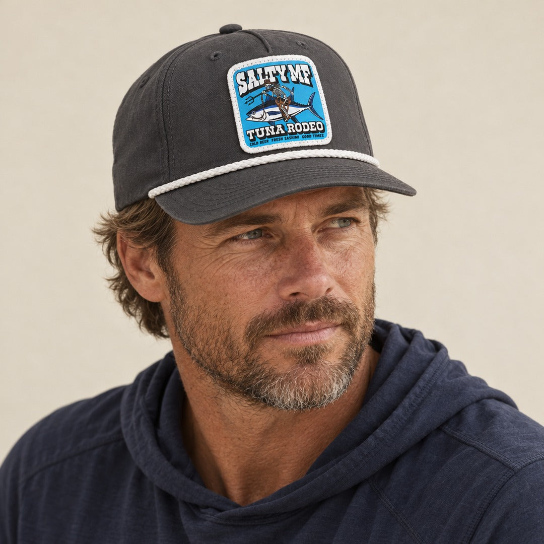 Man wearing the SALTYmf Tuna Rodeo Roper in Gray, three quarter view looking off to the side, with a navy performance hoodie