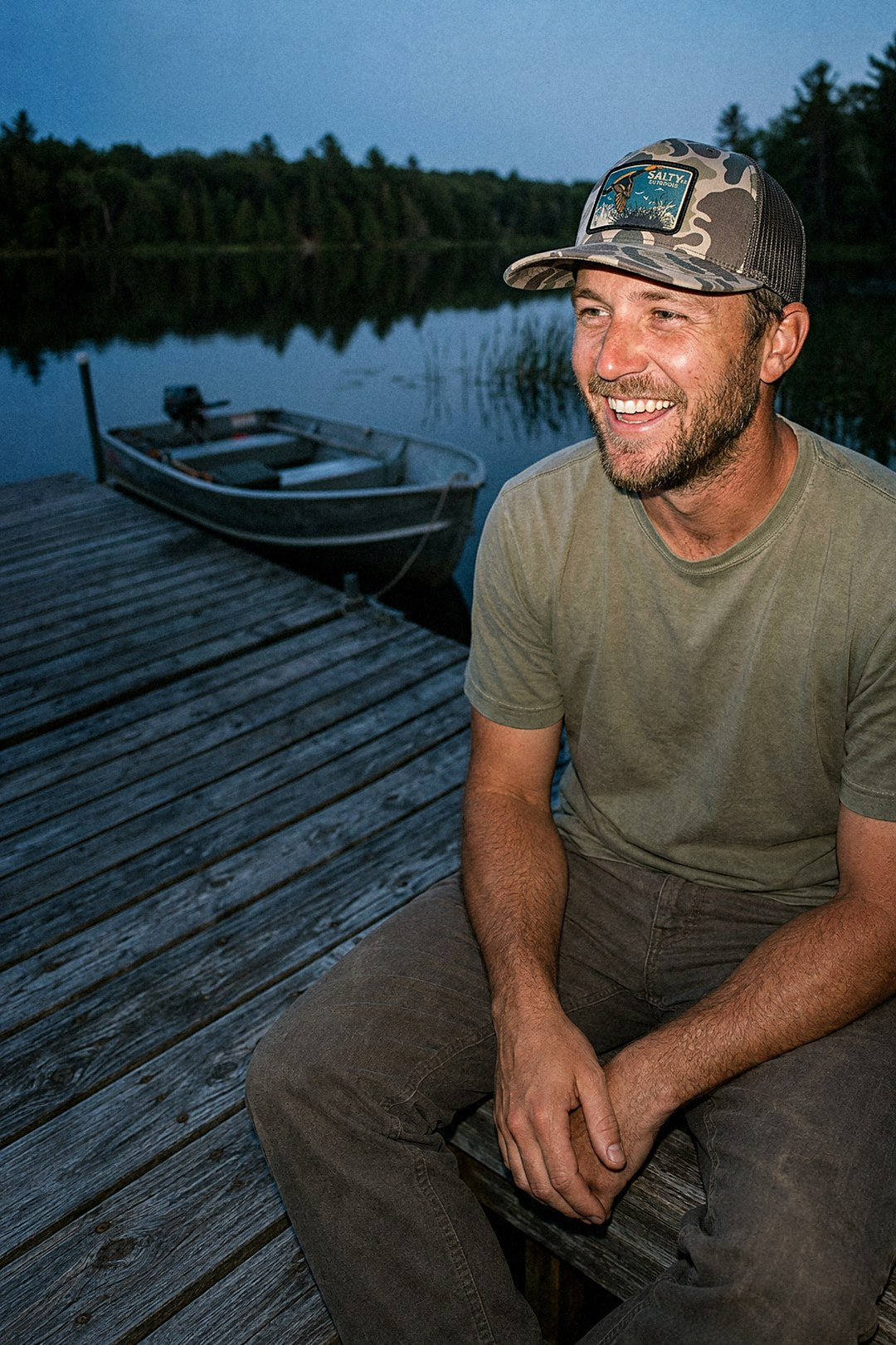 Man in the Woven Duck Patch Trucker in Bark Duck Camo on a lake dock at dusk