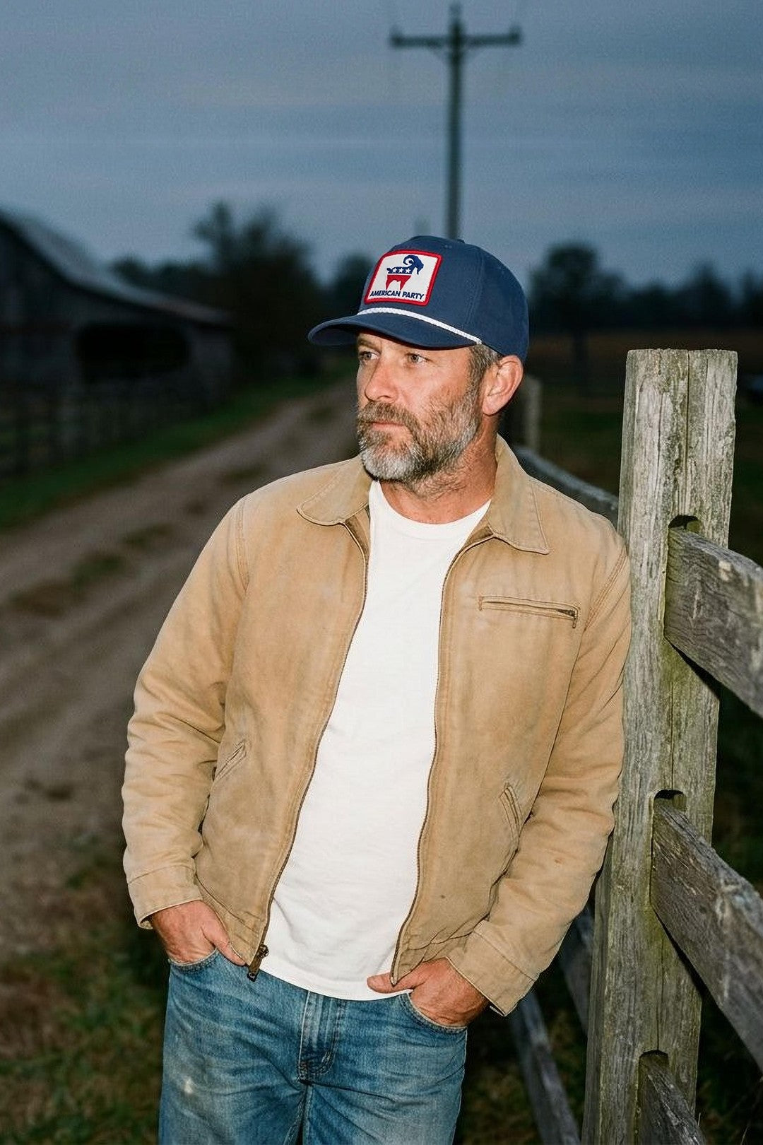 Man in the SALTYmf American Party Patch Rope Hat by a farm fence at dusk
