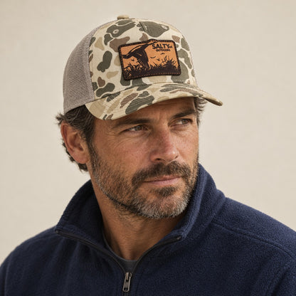 SALTYmf Leather Duck Hunt Patch Trucker in Harvest Duck Camo, worn by a model, three quarter view with the laser-etched leather duck patch