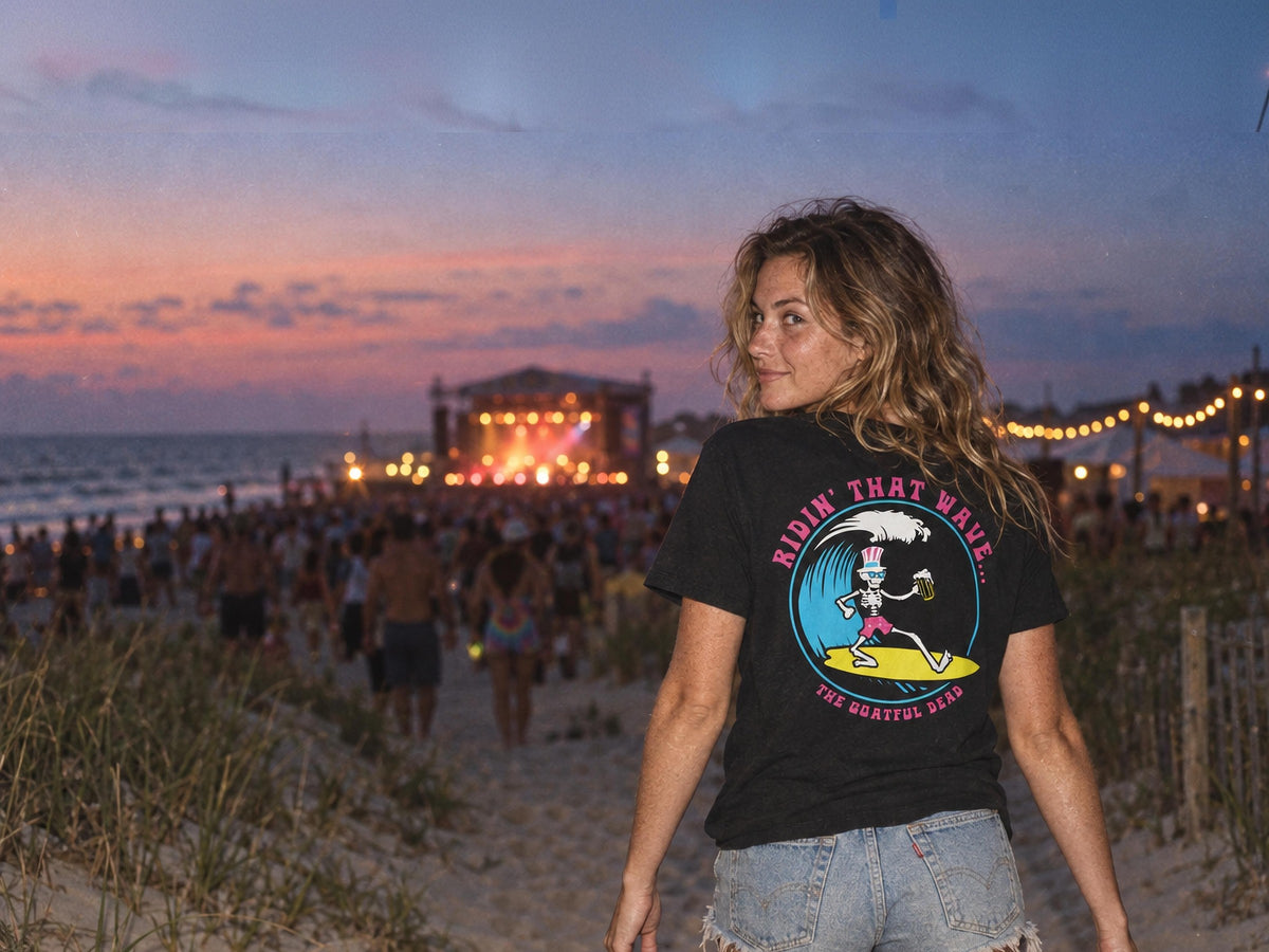 Woman in the SALTYmf Goatful Dead Surf Team Tee at a beach music festival at dusk