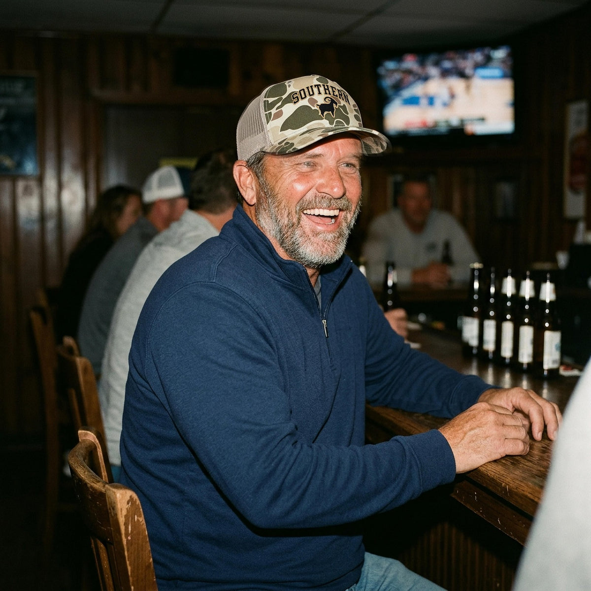 Man in the SALTYmf Southern GOAT Trucker laughing at a sports bar